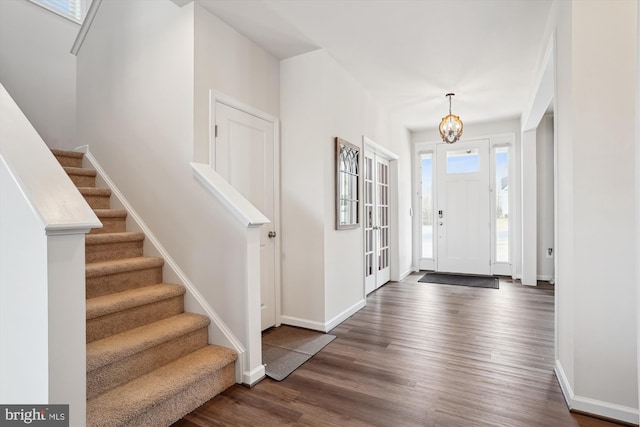 entryway with a notable chandelier, stairs, baseboards, and wood finished floors