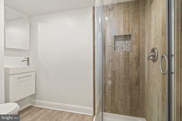 bathroom featuring hardwood / wood-style floors, vanity, toilet, and a shower with shower door