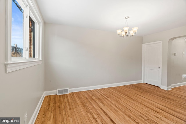 empty room featuring a chandelier and wood-type flooring