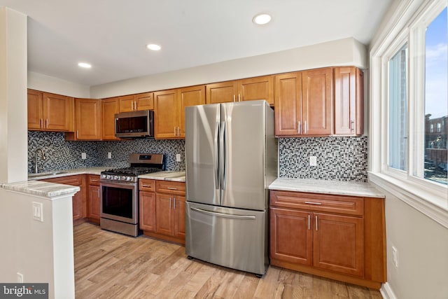 kitchen with decorative backsplash, sink, stainless steel appliances, and light hardwood / wood-style flooring