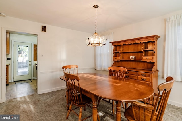 dining space featuring dark colored carpet and a chandelier