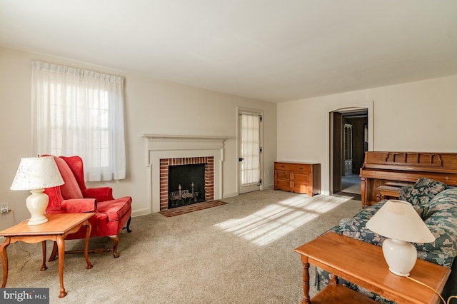 carpeted living room with a brick fireplace