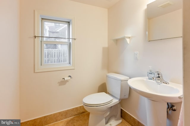 bathroom with toilet, tile patterned flooring, and sink