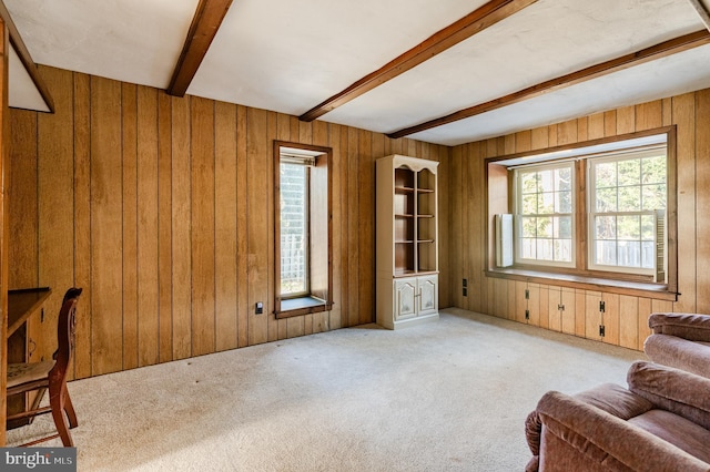 living area featuring beam ceiling, wooden walls, and light carpet