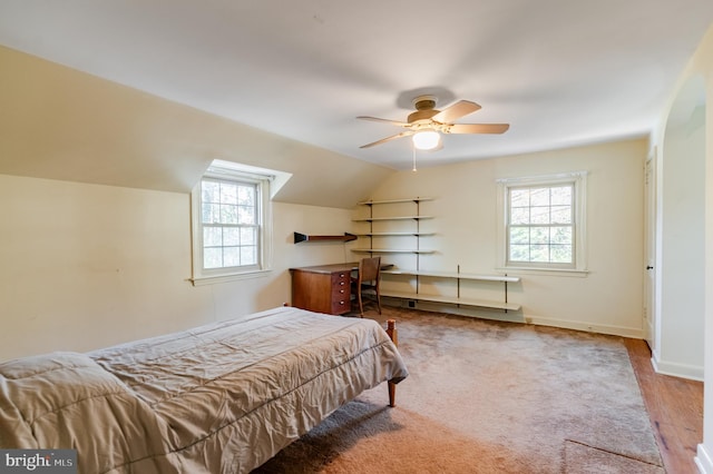 bedroom with ceiling fan, vaulted ceiling, multiple windows, and wood-type flooring