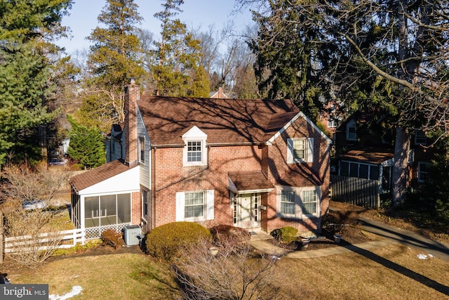 view of front of property with central AC unit, a front lawn, and a sunroom