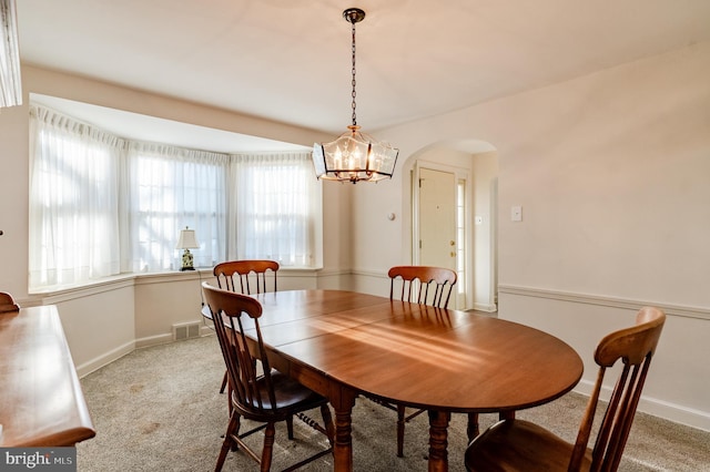 dining space featuring light colored carpet and an inviting chandelier