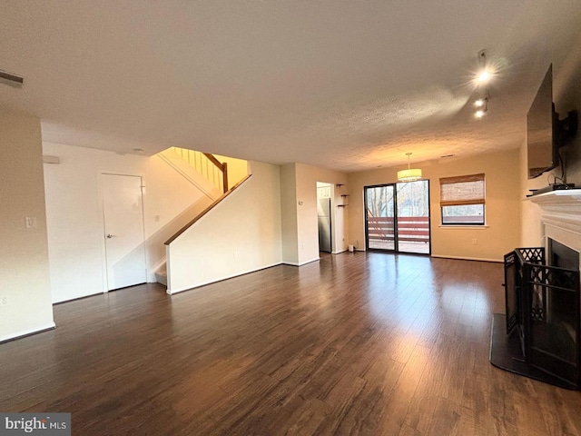 unfurnished living room featuring dark hardwood / wood-style flooring and a textured ceiling