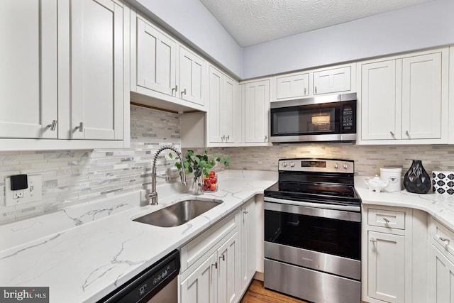 kitchen featuring white cabinets, light stone counters, sink, and stainless steel appliances