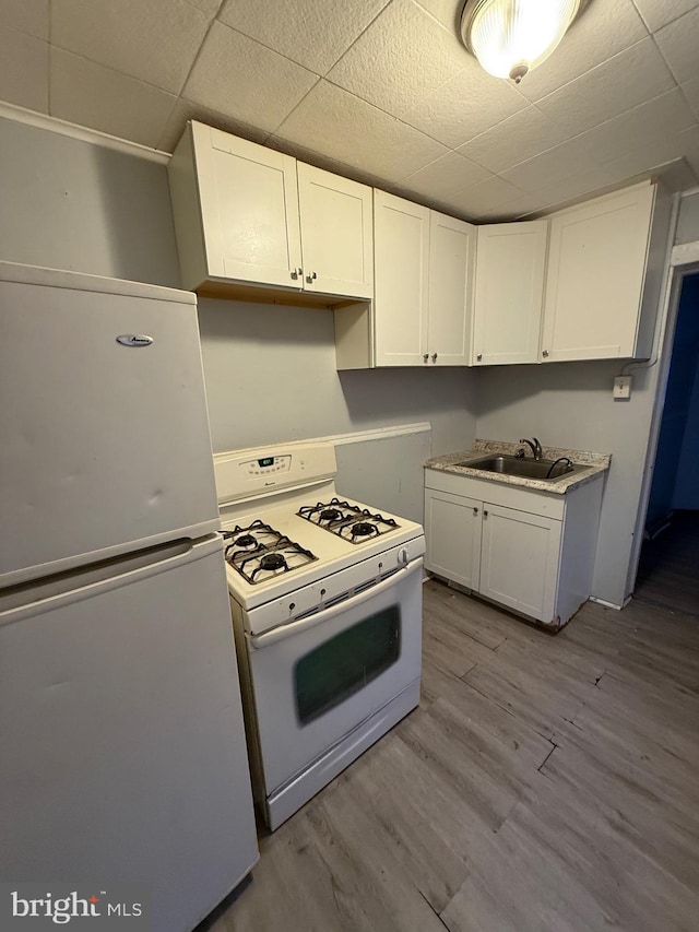 kitchen featuring white cabinetry, light wood-type flooring, white appliances, and sink