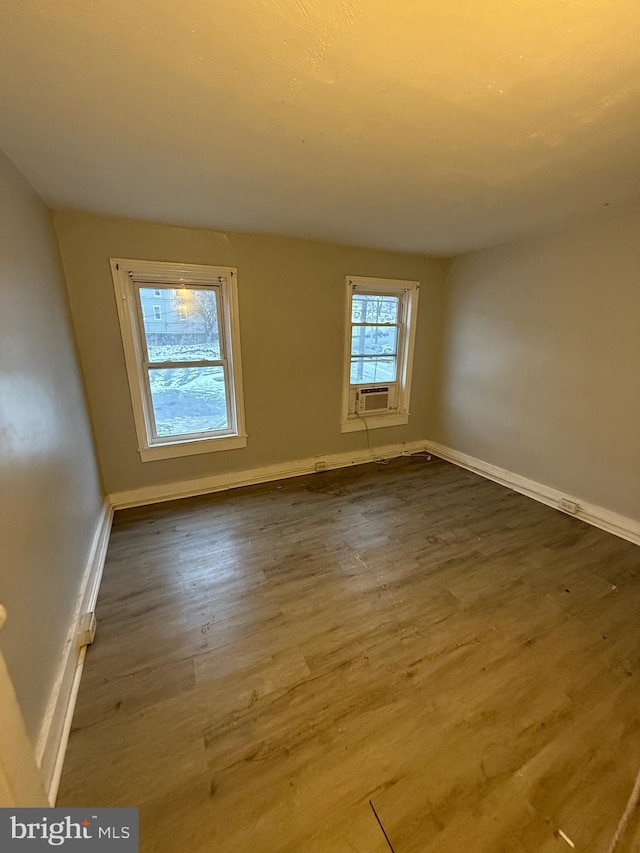 empty room featuring cooling unit and wood-type flooring