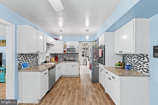 kitchen with sink, stainless steel appliances, white cabinetry, and stone counters