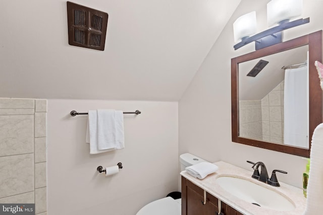 bathroom featuring lofted ceiling, toilet, and vanity