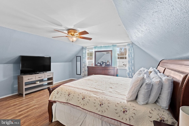 bedroom with a textured ceiling, ceiling fan, vaulted ceiling, and light wood-type flooring