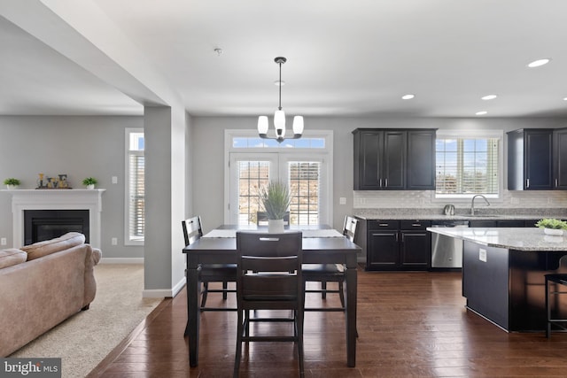 dining space featuring sink, a healthy amount of sunlight, dark hardwood / wood-style floors, and a notable chandelier