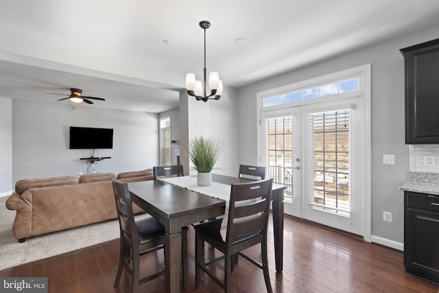 dining area featuring dark wood-type flooring, ceiling fan with notable chandelier, and french doors