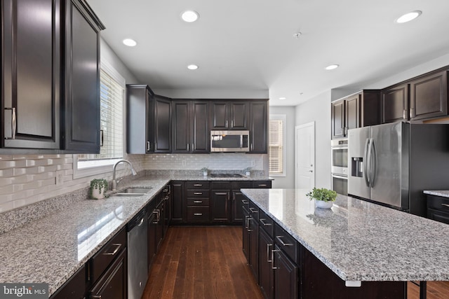 kitchen with a center island, appliances with stainless steel finishes, decorative backsplash, sink, and dark hardwood / wood-style flooring