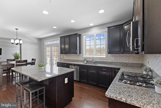 kitchen with dark hardwood / wood-style flooring, sink, appliances with stainless steel finishes, a center island, and decorative backsplash