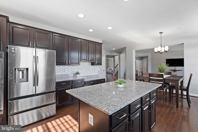 kitchen with stainless steel appliances, a kitchen island, and dark brown cabinetry