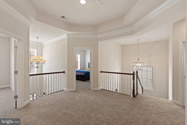 corridor featuring a notable chandelier, ornamental molding, carpet floors, and a tray ceiling