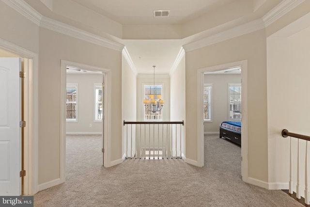 hall with light colored carpet, ornamental molding, a chandelier, and a healthy amount of sunlight