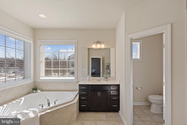 bathroom featuring vanity, toilet, and tiled tub