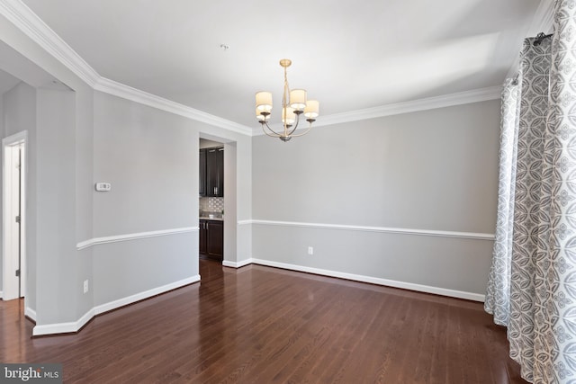 unfurnished room featuring dark hardwood / wood-style floors, ornamental molding, and a notable chandelier