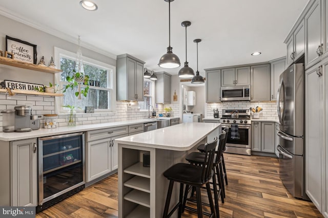 kitchen with hanging light fixtures, a kitchen island, gray cabinets, wine cooler, and appliances with stainless steel finishes