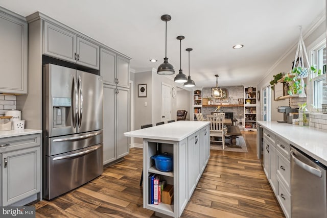 kitchen featuring stainless steel appliances, a center island, gray cabinets, and crown molding