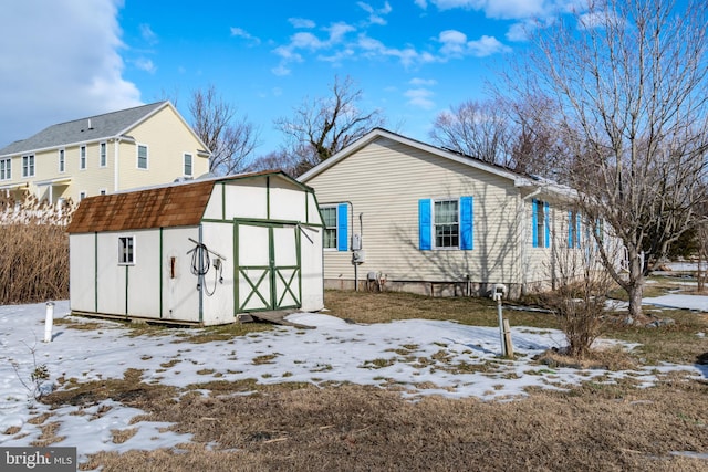 snow covered back of property with a storage shed