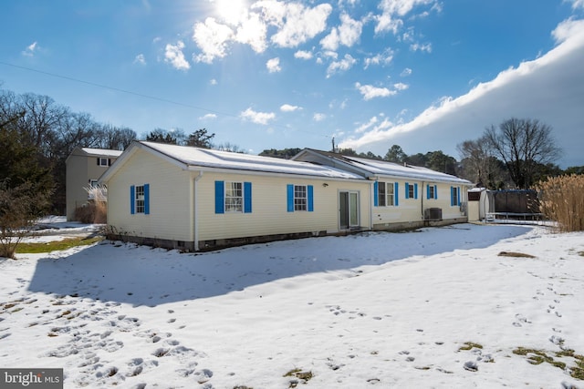 snow covered back of property featuring central AC unit and a trampoline