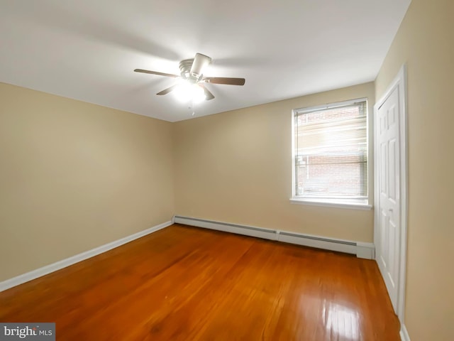 empty room with ceiling fan, hardwood / wood-style floors, and a baseboard heating unit