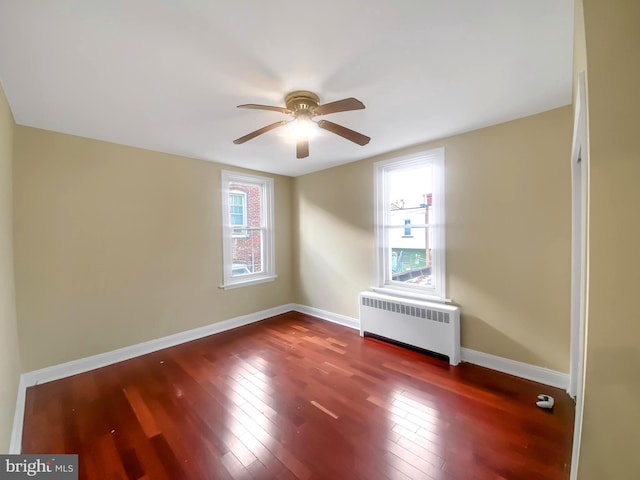 spare room featuring radiator heating unit, dark hardwood / wood-style flooring, a wealth of natural light, and ceiling fan