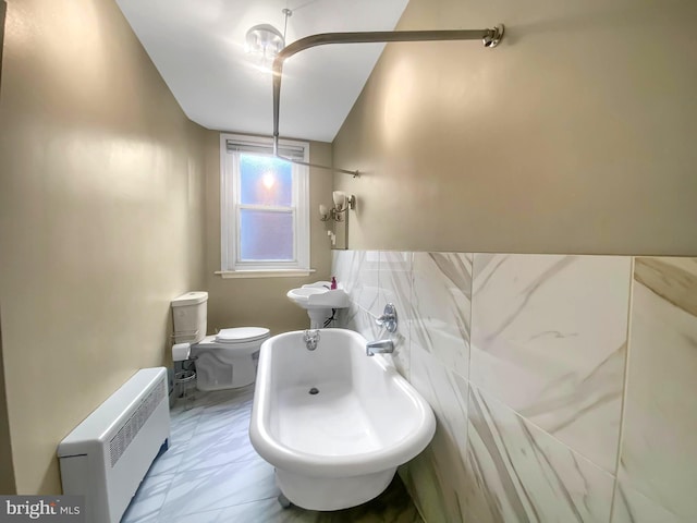 bathroom with a tub to relax in, radiator, and toilet