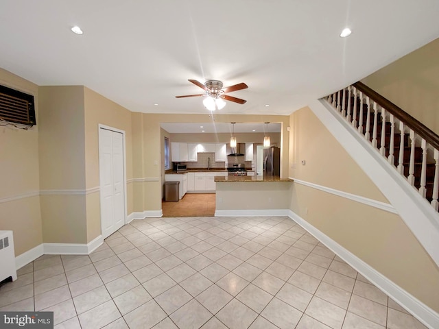 unfurnished living room with ceiling fan, light tile patterned flooring, and radiator heating unit