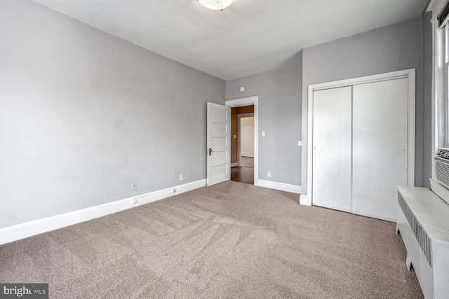 unfurnished bedroom featuring carpet floors, radiator heating unit, and a closet