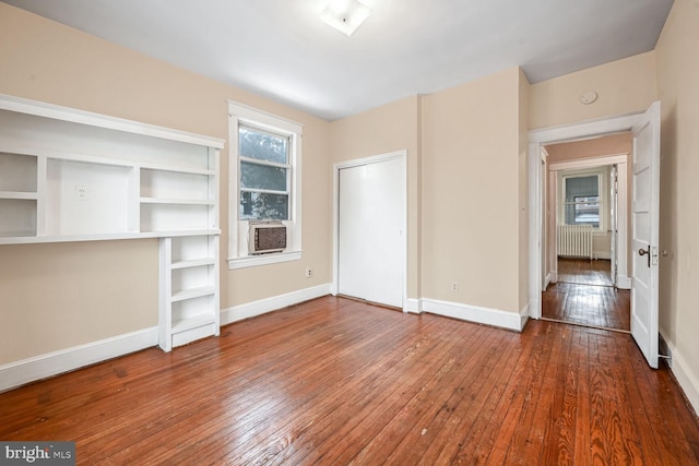 unfurnished living room with cooling unit, radiator, and wood-type flooring