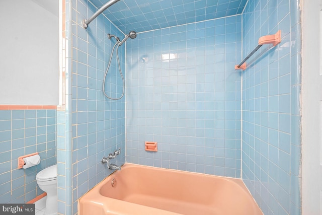 bathroom with tile walls, toilet, and tiled shower / bath