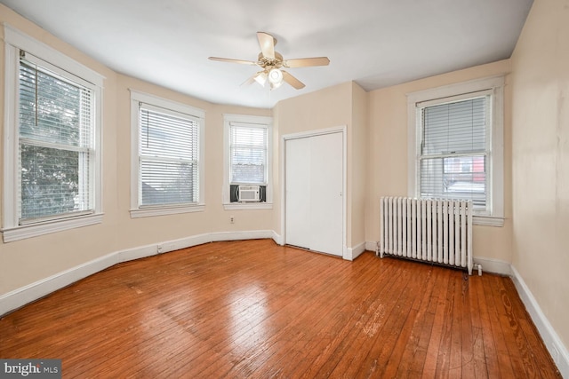 spare room with plenty of natural light, radiator, hardwood / wood-style floors, and ceiling fan