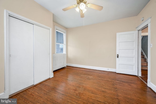 unfurnished bedroom featuring wood-type flooring, radiator heating unit, a closet, and ceiling fan