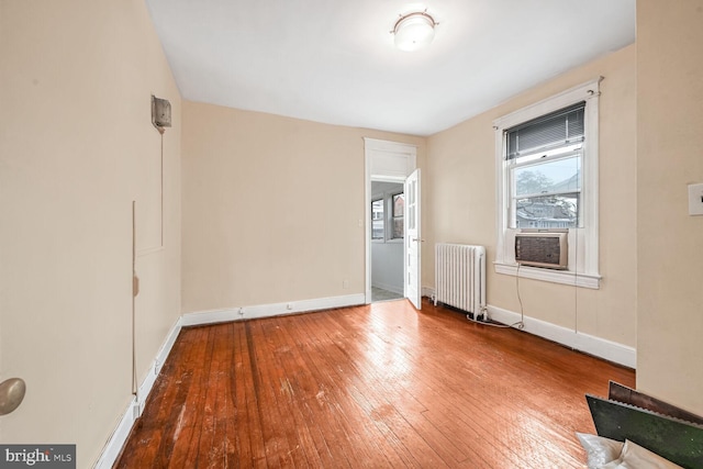 spare room featuring hardwood / wood-style floors, radiator heating unit, and cooling unit