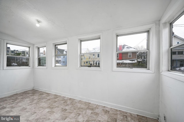 spare room with lofted ceiling, a wealth of natural light, and a textured ceiling