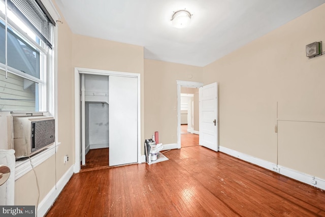 unfurnished bedroom featuring cooling unit, hardwood / wood-style floors, and a closet