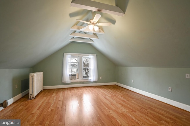 additional living space featuring vaulted ceiling, radiator, ceiling fan, and light wood-type flooring