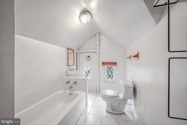 bathroom featuring lofted ceiling, a tub to relax in, toilet, sink, and tile patterned flooring