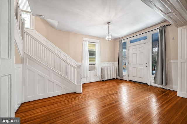 foyer featuring hardwood / wood-style floors, a wealth of natural light, radiator heating unit, and an inviting chandelier