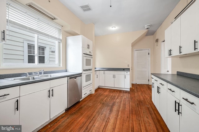 kitchen with white cabinetry, sink, stainless steel dishwasher, and dark hardwood / wood-style floors