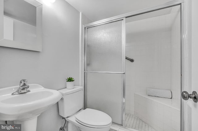 bathroom featuring toilet, a shower with shower door, and sink