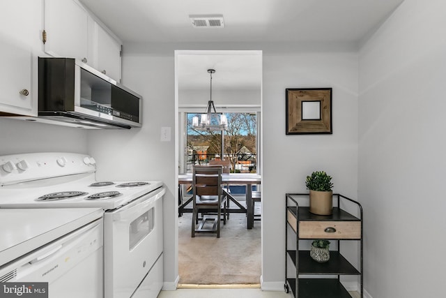 kitchen with white appliances, pendant lighting, a notable chandelier, light colored carpet, and white cabinetry