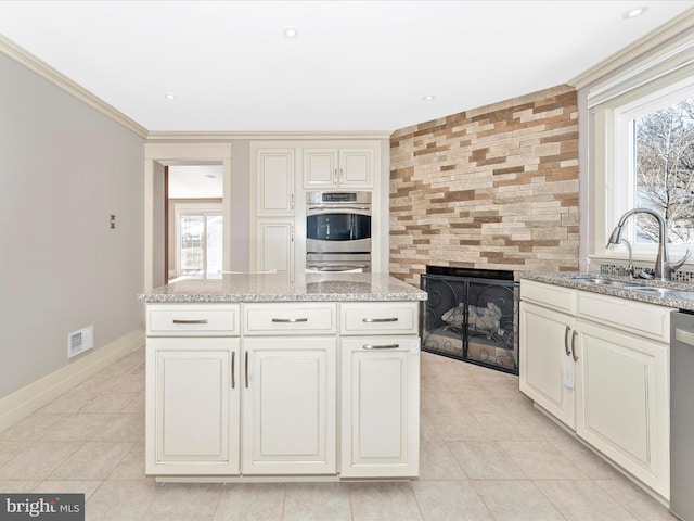 kitchen with light stone countertops, appliances with stainless steel finishes, sink, and a healthy amount of sunlight